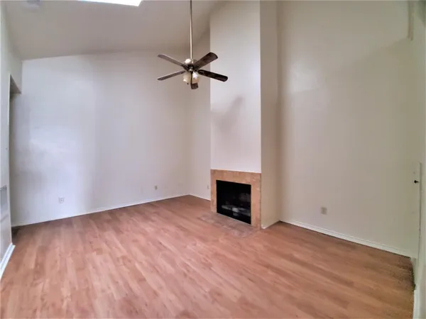 a view of empty room with wooden floor and fireplace