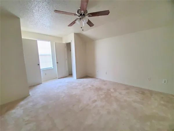 an empty room with chandelier fan and windows