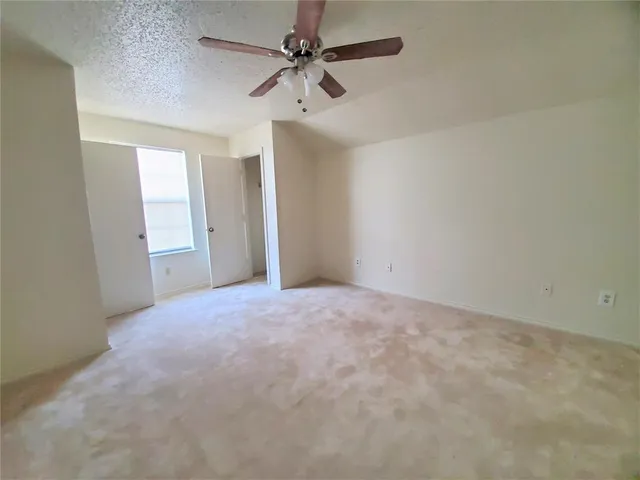 an empty room with chandelier fan and windows