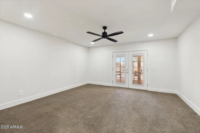an empty room with chandelier fan and windows