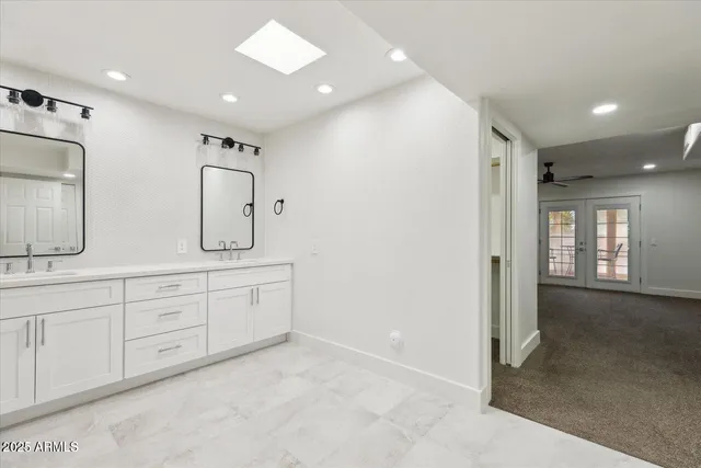 a spacious bathroom with double vanity and a mirror