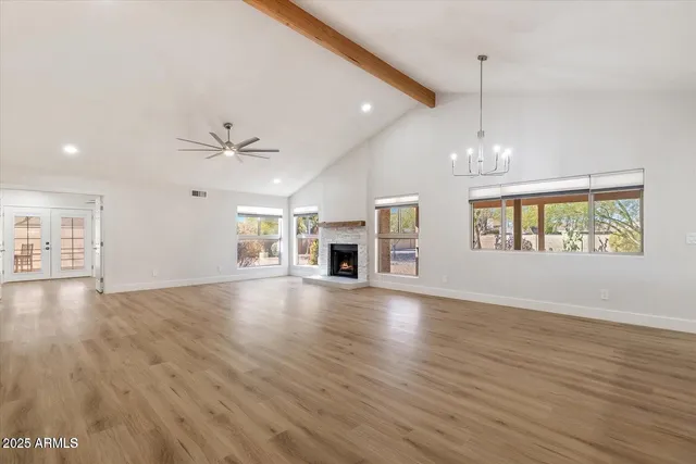 an empty room with wooden floor fireplace and windows