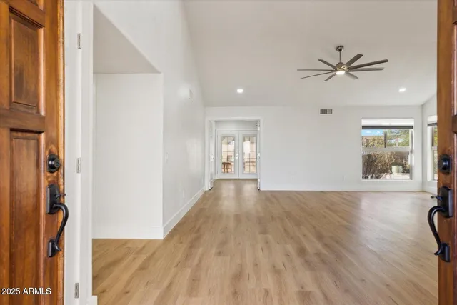 a view of a hallway with wooden floor and a chandelier fan