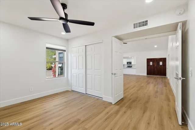 a view of empty room with wooden floor and fan