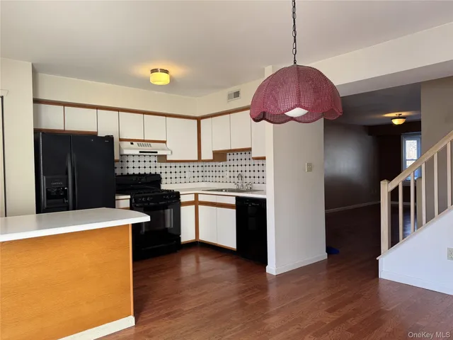 a kitchen with granite countertop a refrigerator a stove top oven a sink and dishwasher with wooden floor