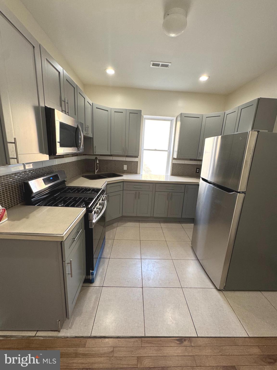 a kitchen with stainless steel appliances a stove a sink a microwave a refrigerator and cabinets
