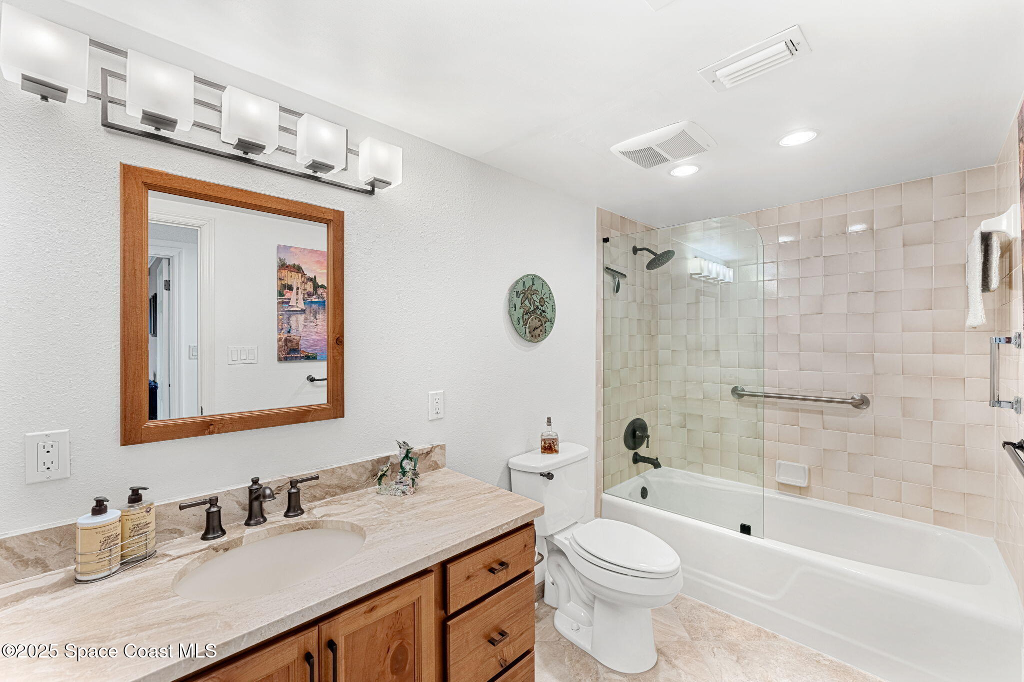 2220 Front Street, Unit 404 Melbourne, FL 32901 - Photo 45 of 52 a bathroom with a granite countertop sink a toilet a mirror a bathtub and shower