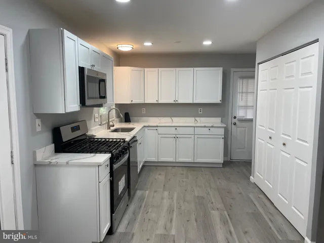 a kitchen with white cabinets stainless steel appliances and sink