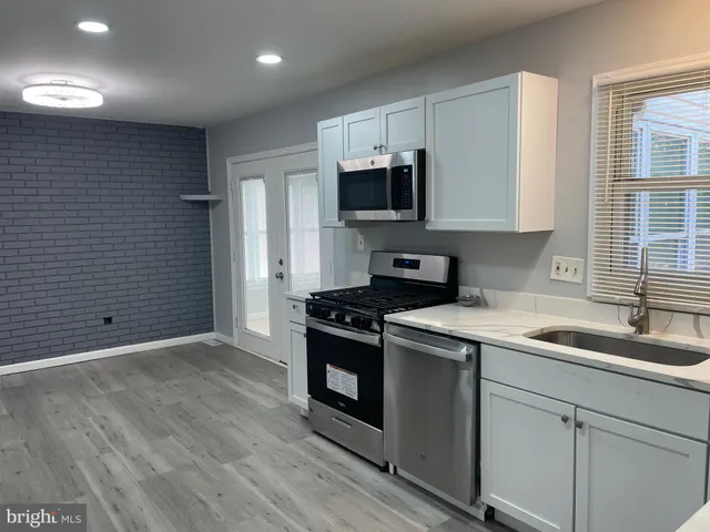 a kitchen with granite countertop a sink stainless steel appliances and cabinets