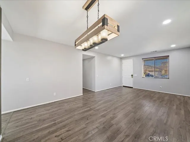 a view of an empty room with wooden floor and a ceiling fan