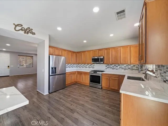 a large kitchen with a large counter top a sink stainless steel appliances and cabinets