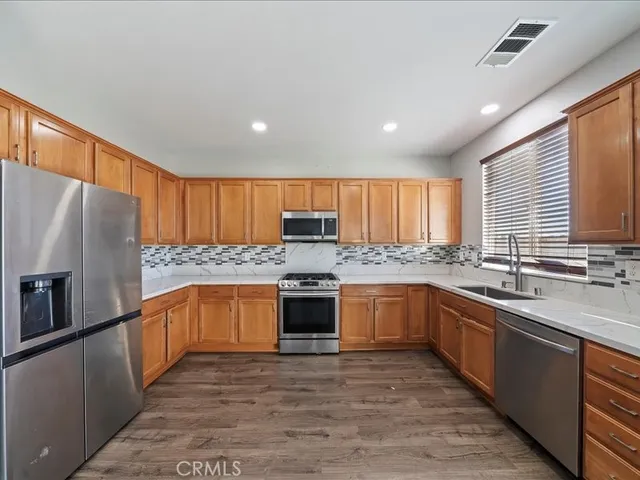 a large kitchen with stainless steel appliances granite countertop a sink counter space cabinets and a large window