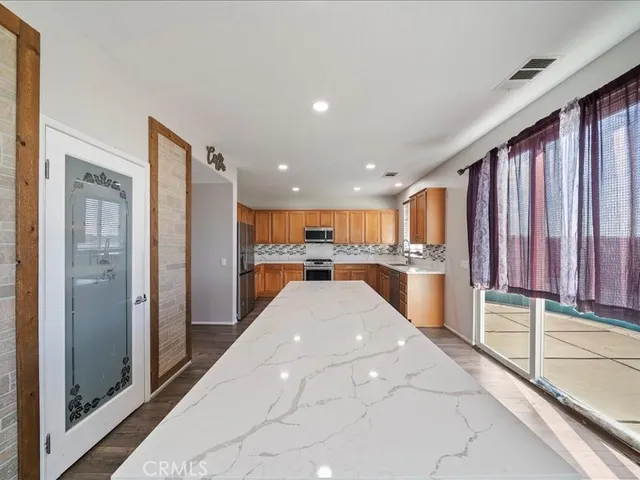 a view of kitchen with kitchen island granite countertop a refrigerator and a sink