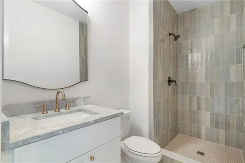 a bathroom with a granite countertop sink a toilet and shower