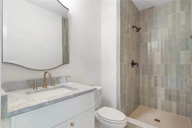a bathroom with a granite countertop sink a toilet and shower