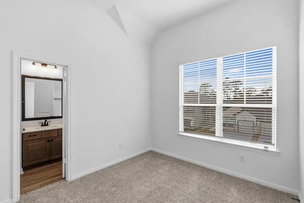 a view of an empty room with a window and kitchen view
