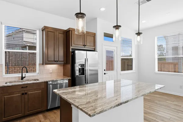 a kitchen with stainless steel appliances granite countertop a sink a refrigerator and a granite counter tops