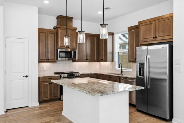 a kitchen with stainless steel appliances granite countertop a refrigerator a sink and a stove