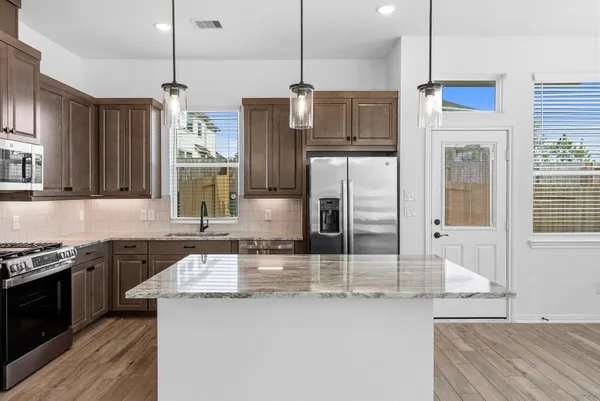 a kitchen with stainless steel appliances granite countertop a sink a stove and a refrigerator