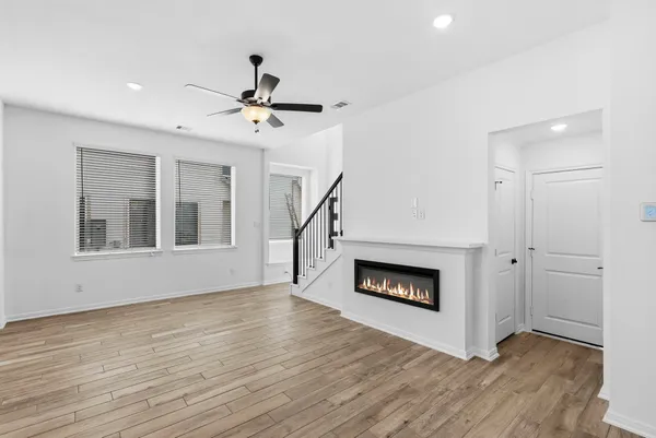 a view of an empty room with wooden floor fireplace and a window