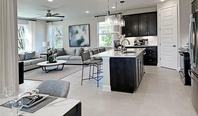 a kitchen with stainless steel appliances a refrigerator a stove a sink and chairs