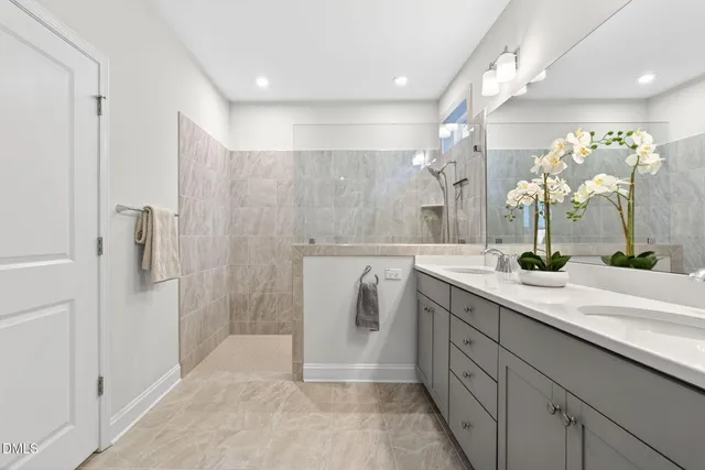 a spacious bathroom with a double vanity sink a large mirror a shower and vanity