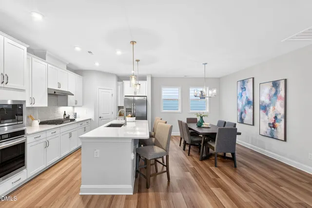 a kitchen with stainless steel appliances kitchen island granite countertop a dining table chairs and white cabinets