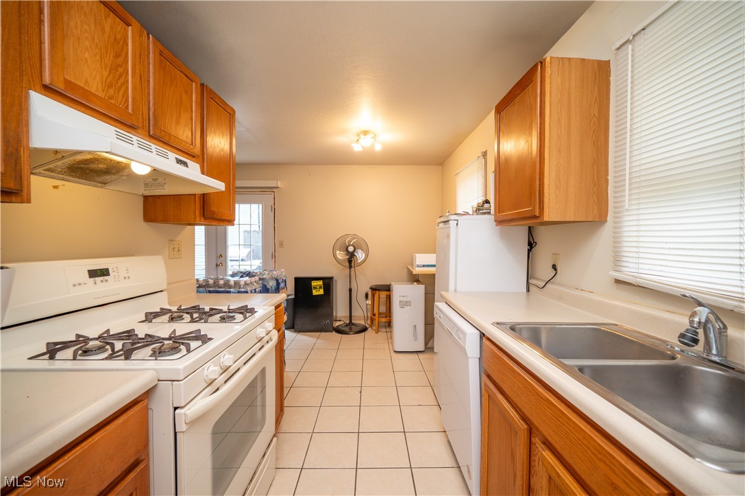5546 Shaffer Road Northwest, Unit A & B Warren, OH 44481 - Photo 23 of 47 Kitchen featuring white appliances, under cabinet range hood, brown cabinets, and light tile patterned floors