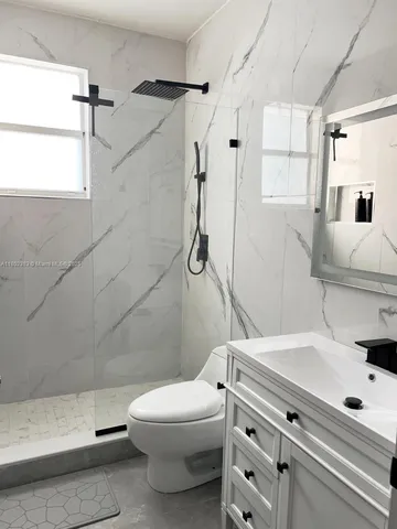 a bathroom with a granite countertop toilet sink and shower