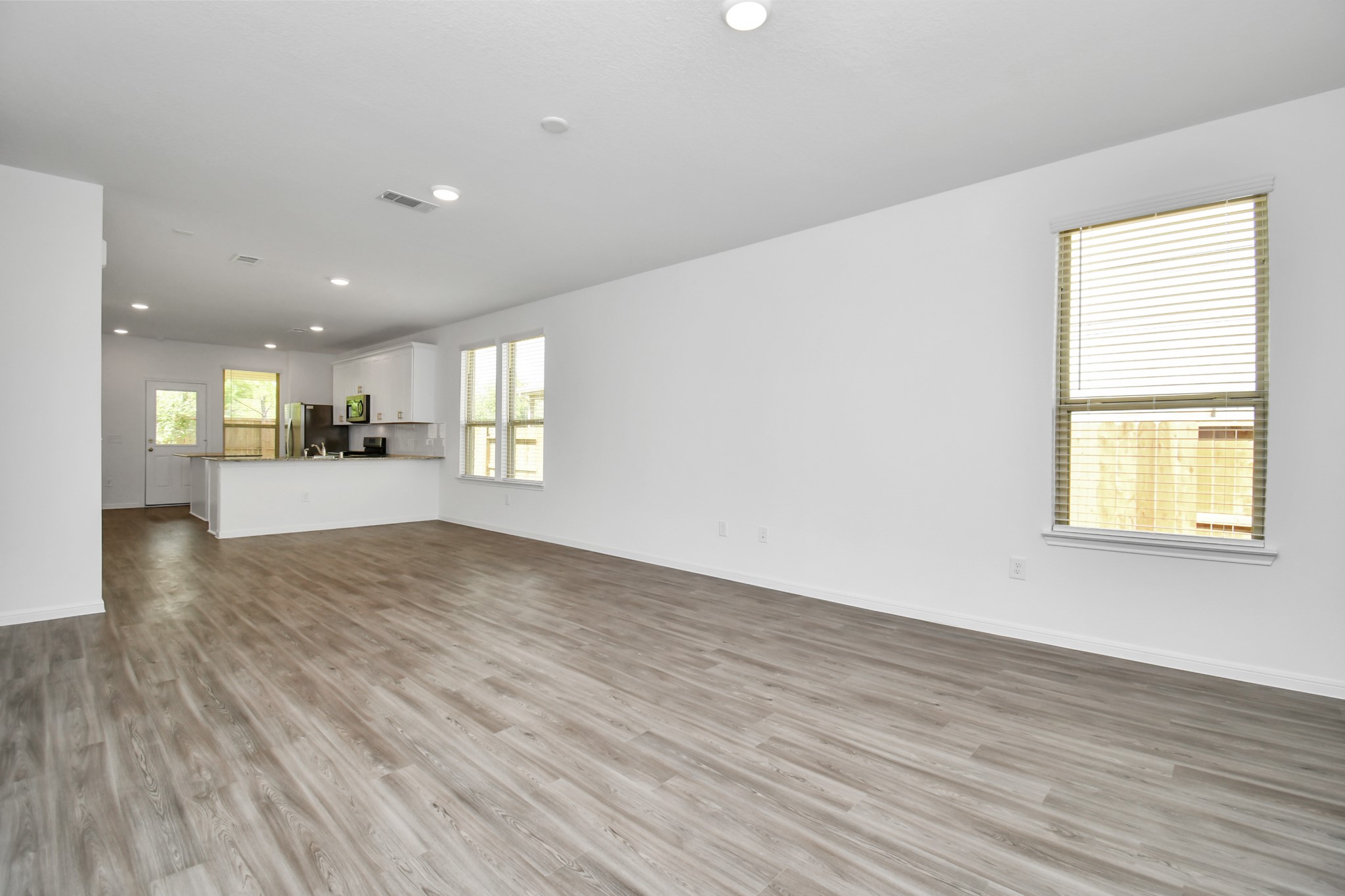 16150 Elbridge Court Conroe, TX 77302 - Photo 5 of 46 Upon stepping inside, you're immediately greeted by an abundance of natural light that bathes the open-concept living space. The interior design is a perfect blend of modern sophistication and warm, inviting elements. High ceilings and large windows create an airy and spacious atmosphere, while gleaming wood style floors flow throughout common areas, adding a touch of luxury.