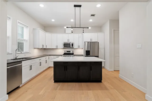 a large kitchen with stainless steel appliances granite countertop a stove a sink and a refrigerator