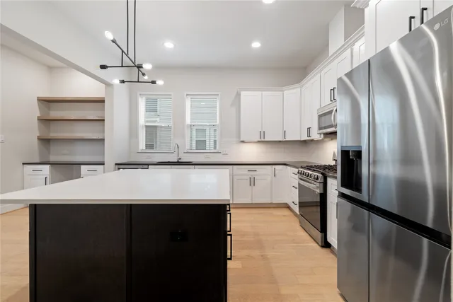 a kitchen with stainless steel appliances kitchen island granite countertop a refrigerator a sink dishwasher a stove and a refrigerator