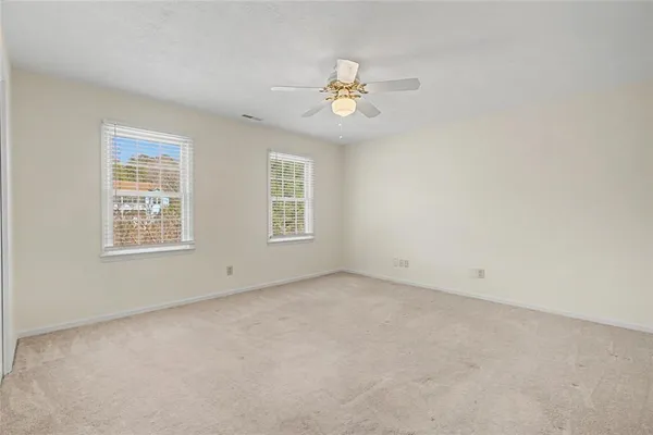 an empty room with wooden floor fireplace and windows