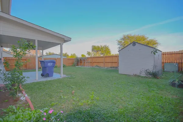 a backyard of a house with table and chairs plants and large tree