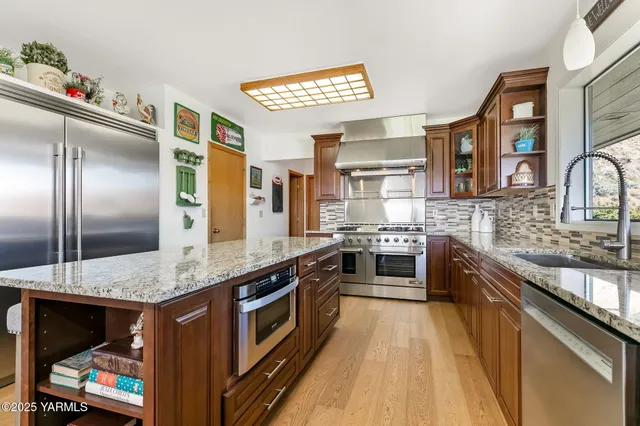 a kitchen with stainless steel appliances granite countertop a table chairs and a refrigerator