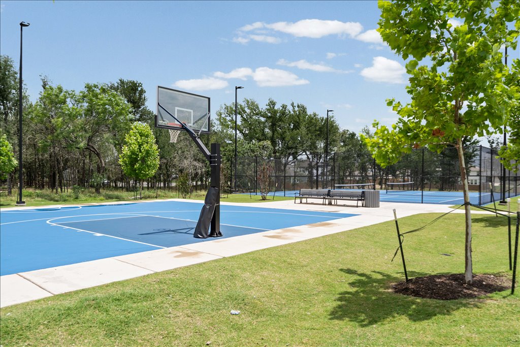 158 Gullivers Drive Elgin, TX 78621 - Photo 35 of 36 There is a half-court basketball setup with a premium glass backboard, and right behind it are two dedicated tennis courts completely enclosed by fencing.