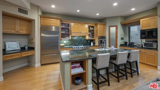 a large kitchen with kitchen island a large counter top space a sink stainless steel appliances and cabinets