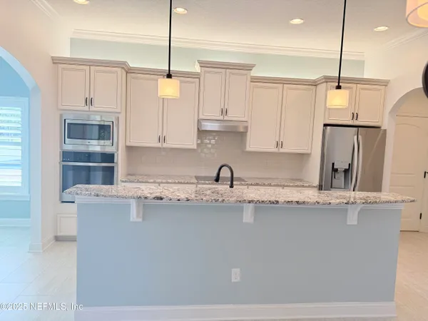 a kitchen with kitchen island a sink a center island a stove and cabinets