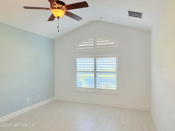 an empty room with windows and fan