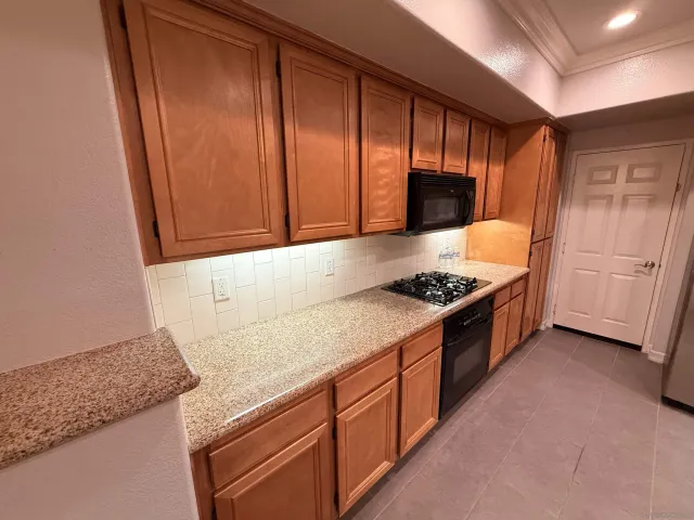 a kitchen with granite countertop stainless steel appliances a sink stove and cabinets