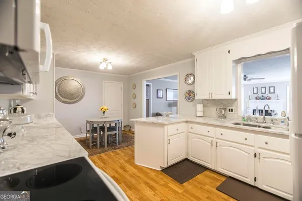 a large white kitchen with cabinets a sink a window and stainless steel appliances