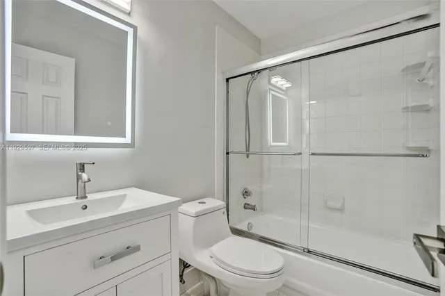 a bathroom with a toilet a sink a mirror and shower