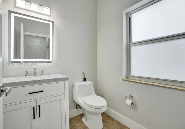a bathroom with a toilet a sink a vanity and mirror