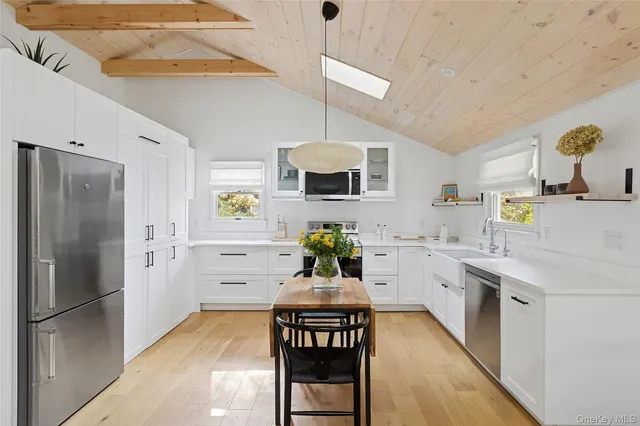 a kitchen with stainless steel appliances granite countertop a refrigerator a stove a sink dishwasher and white cabinets with wooden floor