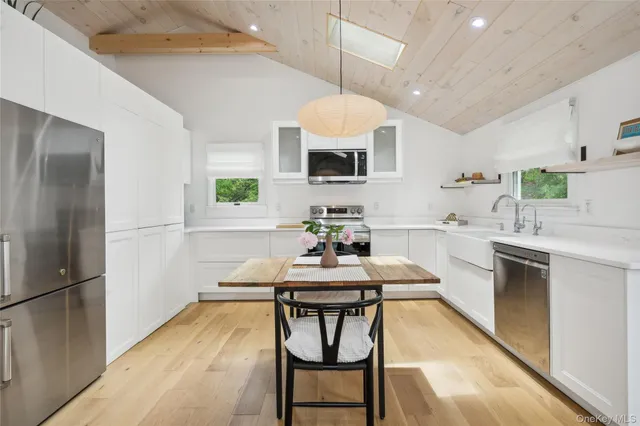 a kitchen with kitchen island a dining table chairs stainless steel appliances and cabinets