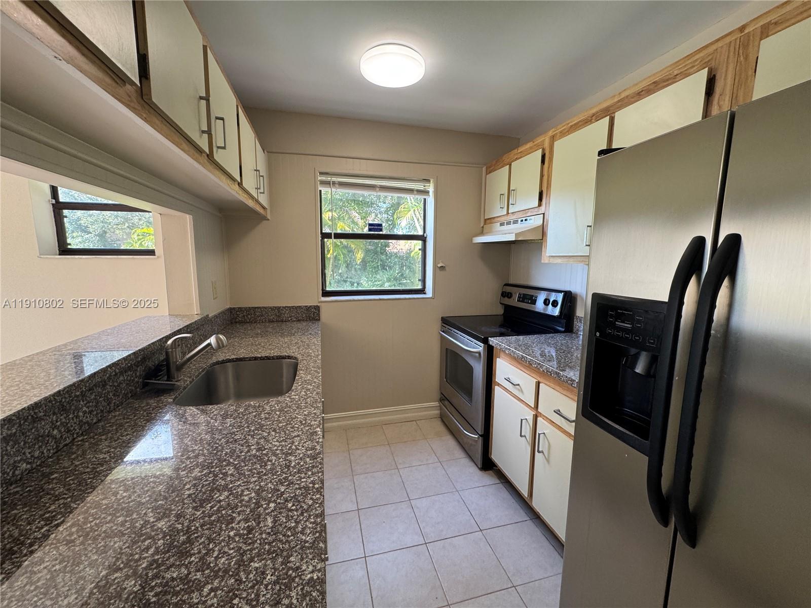6031 Shaker Wood Circle, Unit 101 Tamarac, FL 33319 - Photo 12 of 28 a kitchen with granite countertop a refrigerator and a sink