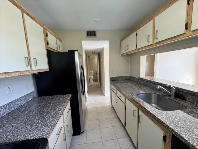 a kitchen with granite countertop stainless steel appliances a sink and a refrigerator