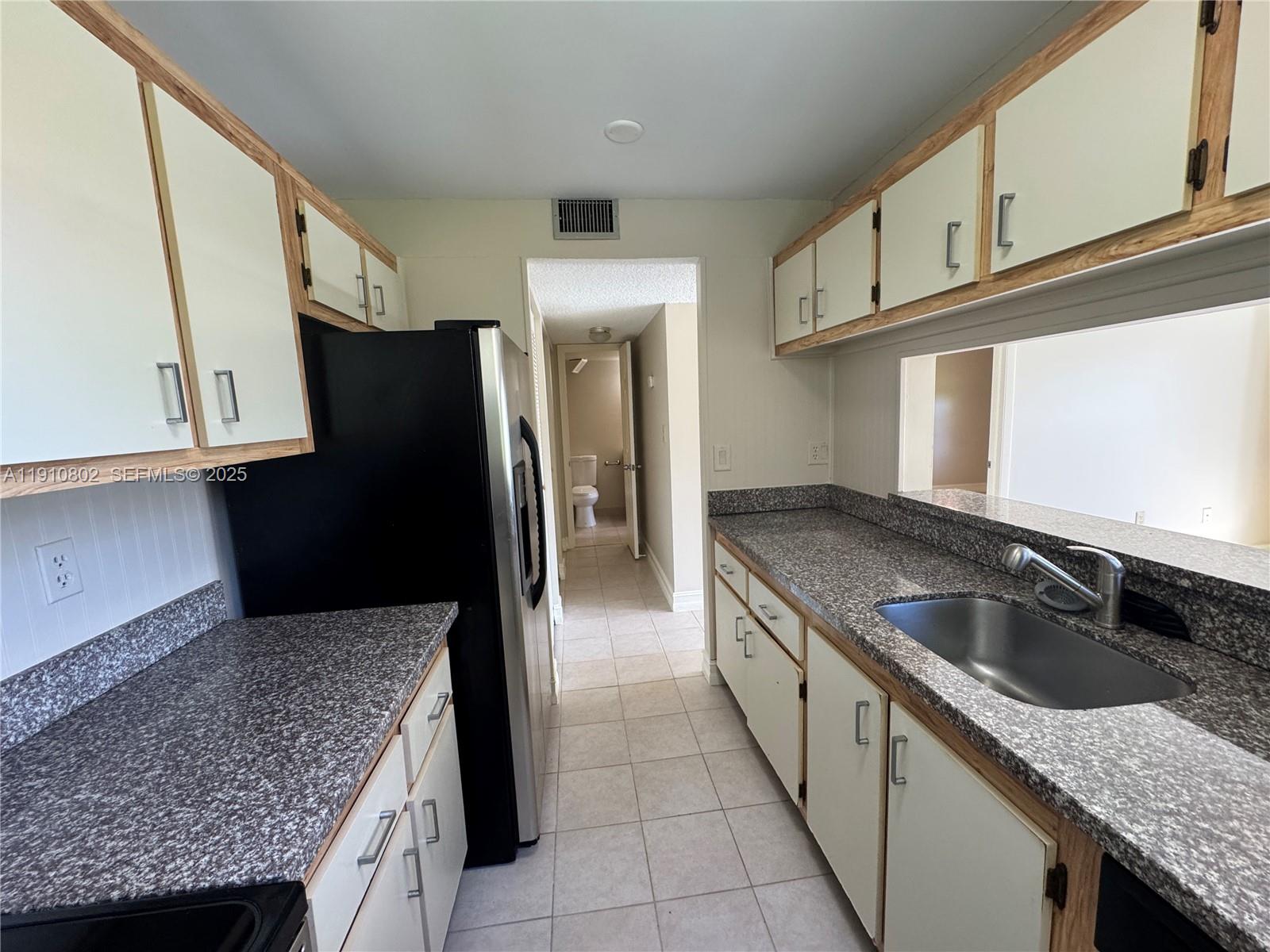 6031 Shaker Wood Circle, Unit 101 Tamarac, FL 33319 - Photo 13 of 28 a kitchen with granite countertop stainless steel appliances a sink and a refrigerator