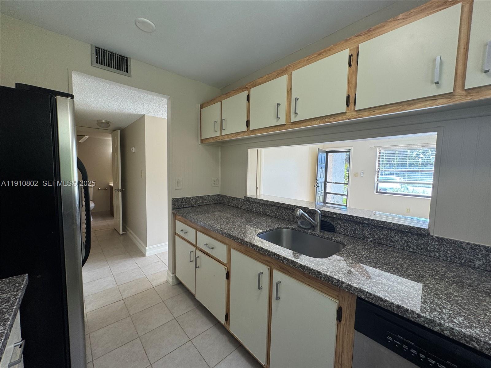 6031 Shaker Wood Circle, Unit 101 Tamarac, FL 33319 - Photo 14 of 28 a kitchen with granite countertop a sink a stove and cabinets