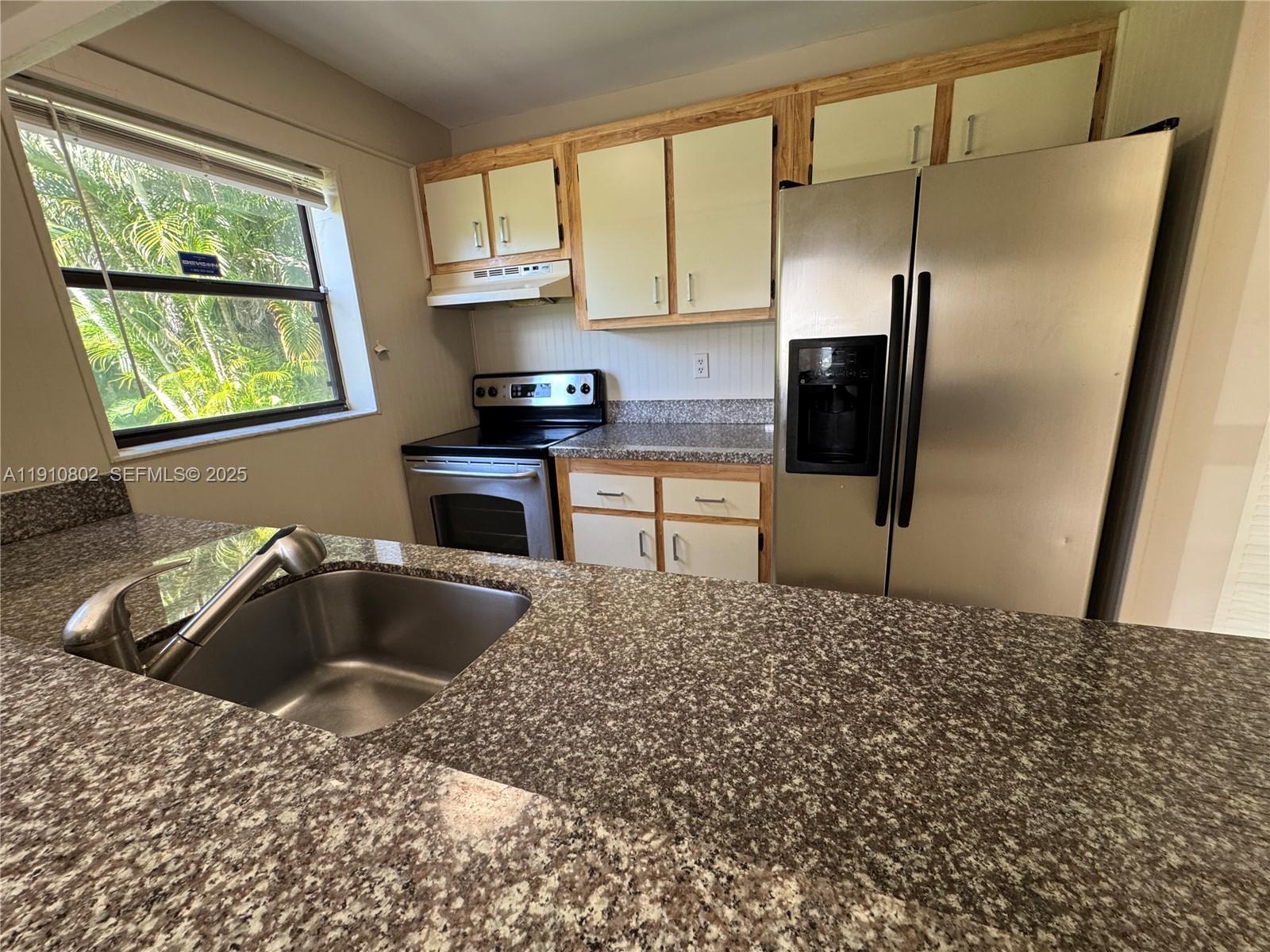 6031 Shaker Wood Circle, Unit 101 Tamarac, FL 33319 - Photo 16 of 28 a kitchen with kitchen island granite countertop a sink cabinets and refrigerator